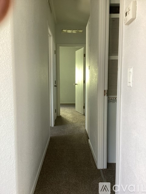 A hallway with white walls and carpeted floor.