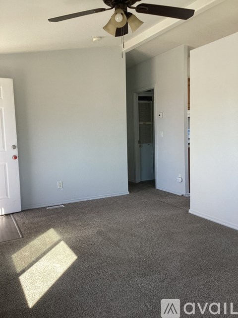 A room with a ceiling fan and a carpeted floor.