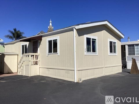 A beige house with a white roof and a tower in the background.