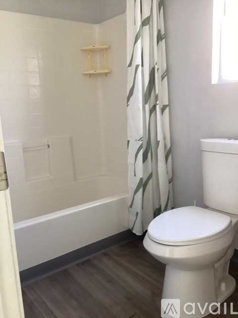 A white toilet in a bathroom with a white tub and a white shower curtain.