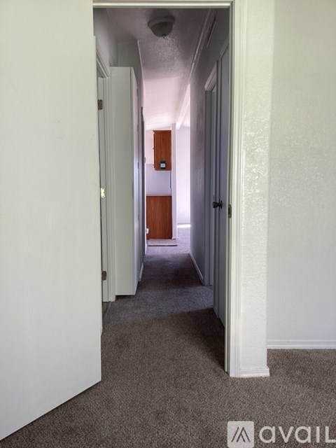 A hallway with a carpeted floor and white walls.