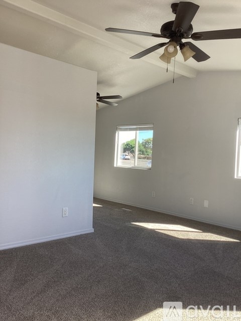 A room with a ceiling fan and carpeted floor.
