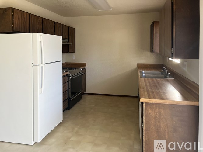 A kitchen with a white fridge and wooden cabinets.