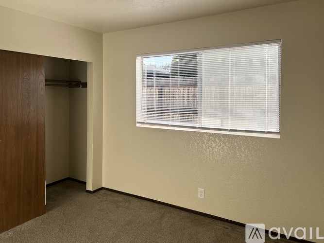 A room with a window covered in blinds and a carpet on the floor.