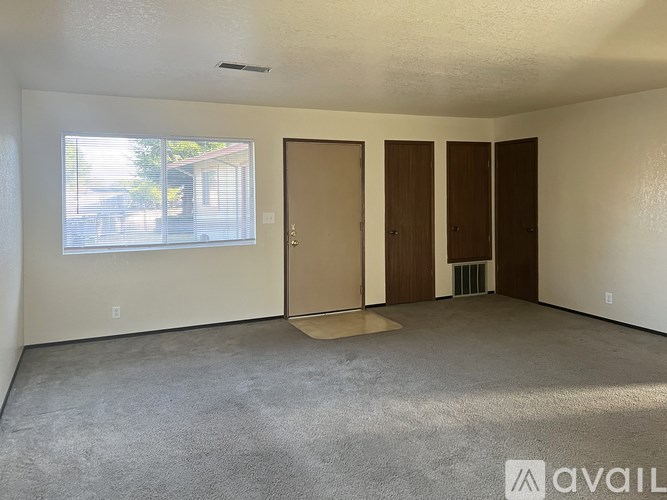 A room with a carpeted floor, a window, and a door.
