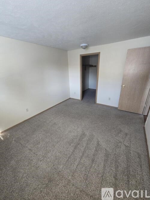 A room with a carpeted floor and a doorway leading to another room.