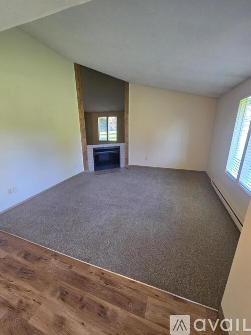 A room with a grey carpet and wooden flooring.