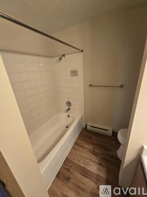 A bathroom with a white tub and wooden floors.