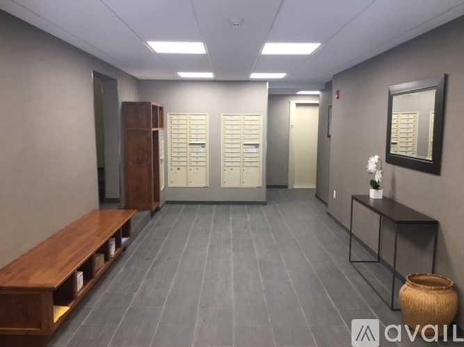 A hallway with a bench, lockers, and a mirror.