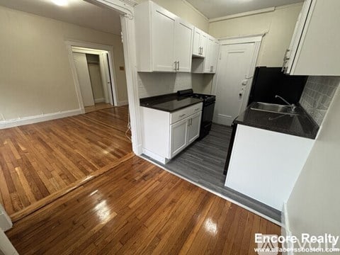 A kitchen with white cabinets and a black countertop.
