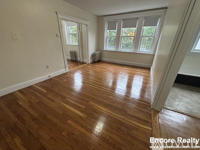 A room with wooden flooring and a window with blinds.