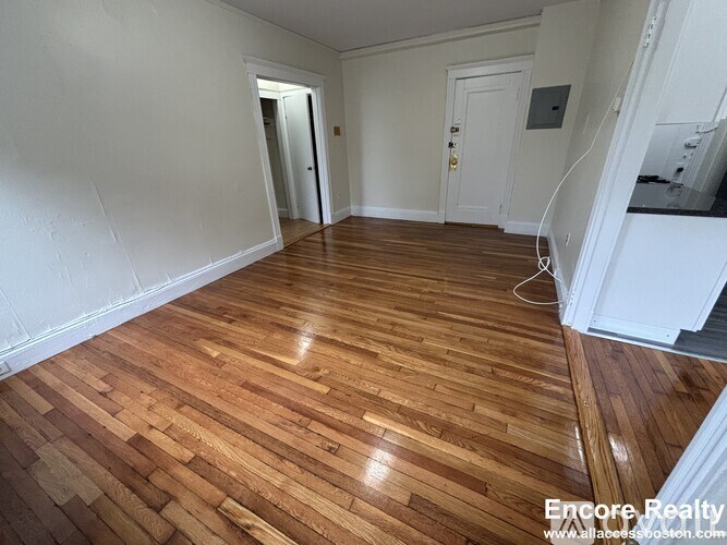 A room with wooden flooring and white walls.