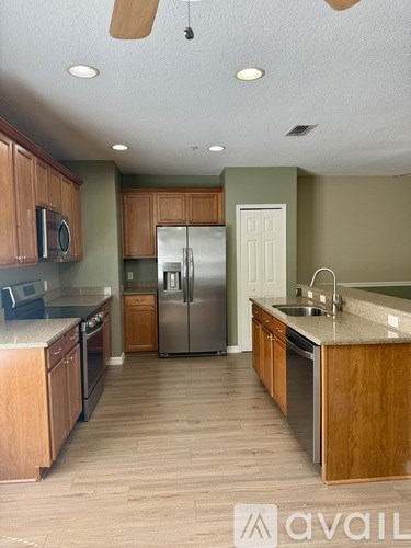 A kitchen with wooden cabinets and a stainless steel refrigerator.