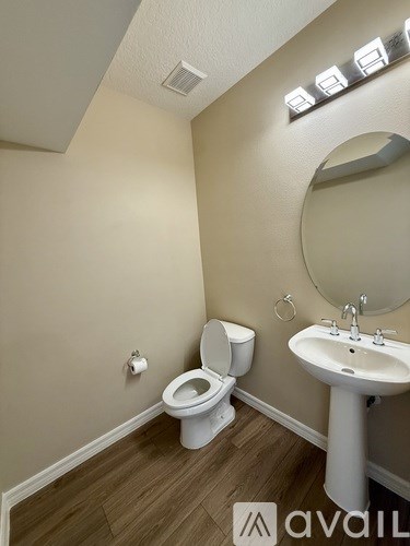 A bathroom with a toilet, sink, and mirror.