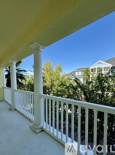 A white porch with a white railing and a blue house in the background.