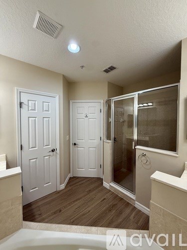 A bathroom with a tub, shower, and two doors.