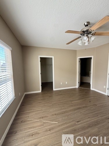 A room with a ceiling fan and two open doors.