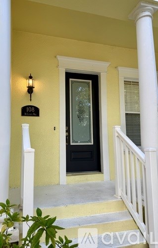 A black door with a glass window is on the front of a yellow building.