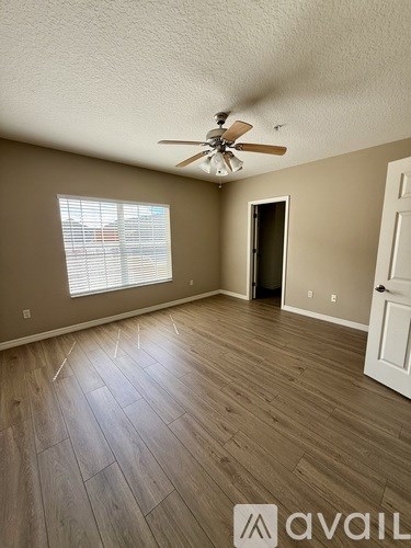 A room with a ceiling fan and wooden flooring.