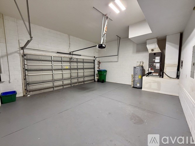 A large, empty garage with a white wall and a grey floor.