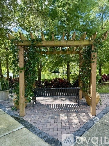 A wooden pergola with vines growing on it is situated in a garden.