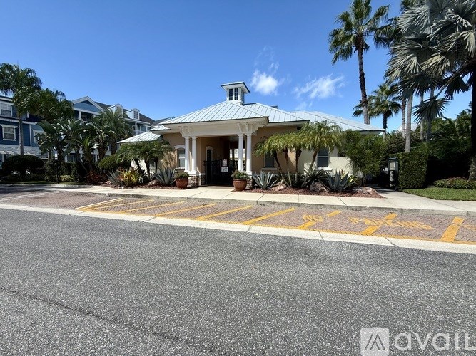 A house with a blue roof and a white porch is surrounded by palm trees.