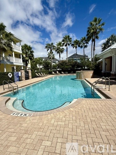 A pool surrounded by palm trees and buildings.
