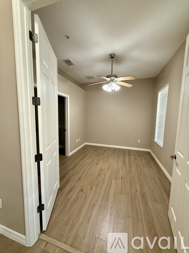 A room with a ceiling fan and wooden flooring.