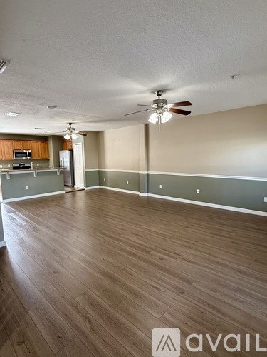 A spacious room with wooden flooring and a ceiling fan.