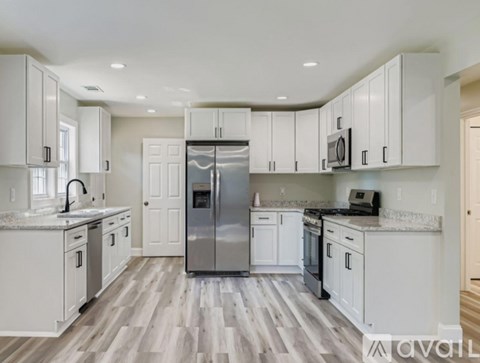 A kitchen with white cabinets and a stainless steel refrigerator.