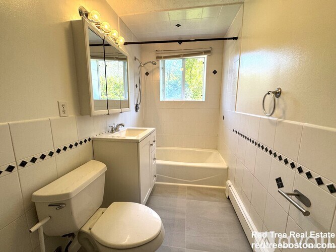 A white toilet is in a bathroom with a white tub and sink.