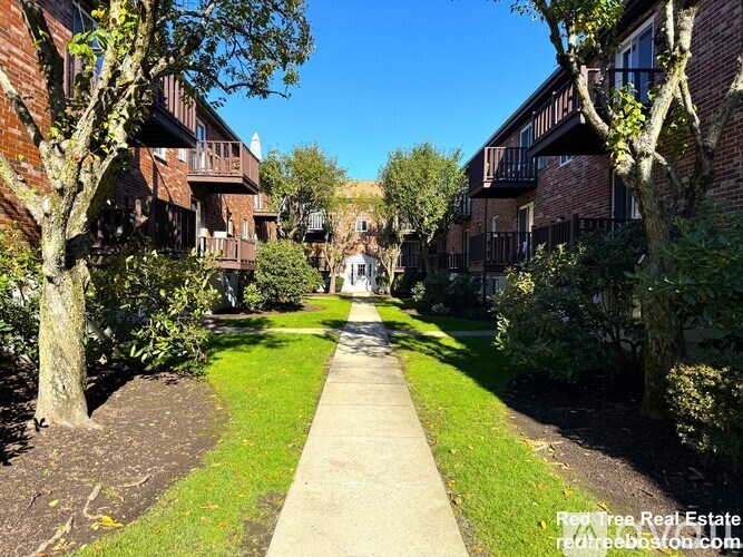 A pathway leads through a grassy area between two rows of buildings.