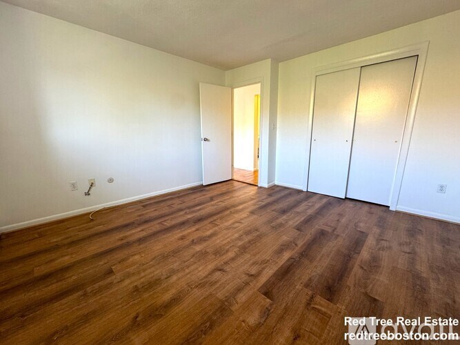 A room with wooden floors and two doors.