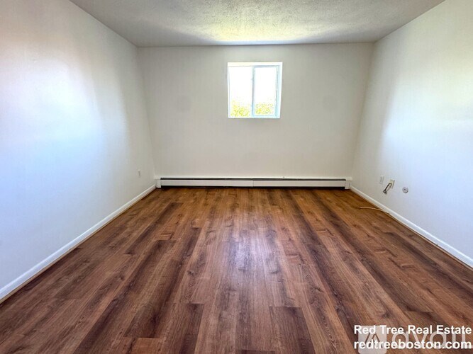 A room with wooden flooring and a window.