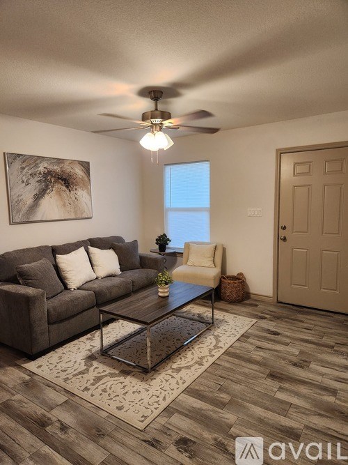 A living room with a grey couch, a coffee table, and a ceiling fan.