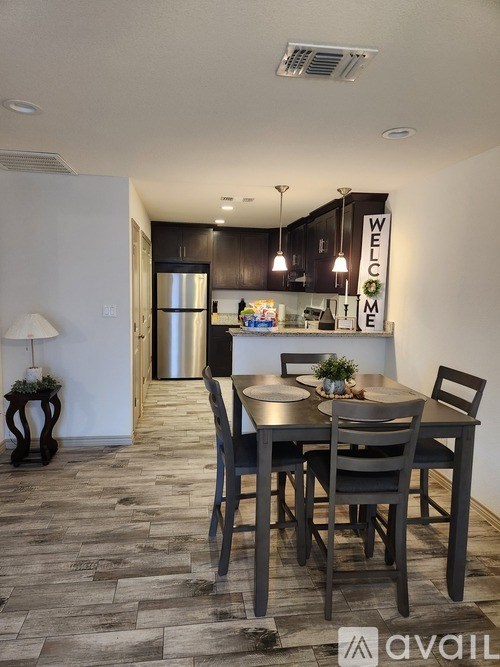 A dining room with a table set for two and a welcome sign on the wall.
