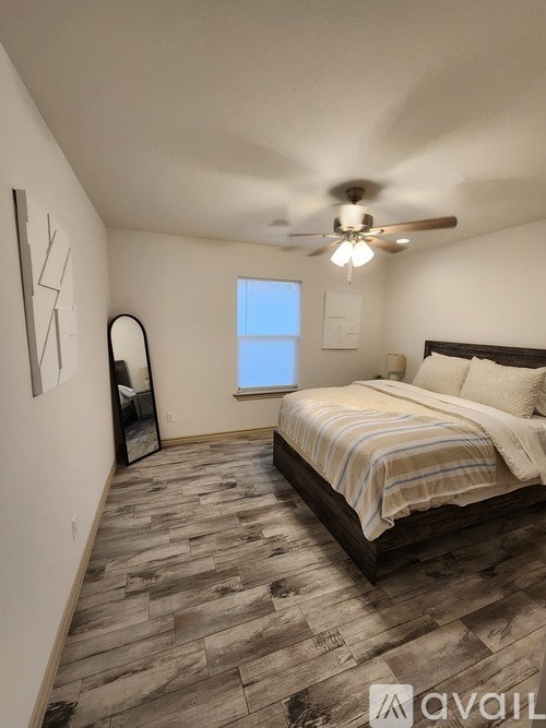 A bedroom with a bed, a ceiling fan, and a window.