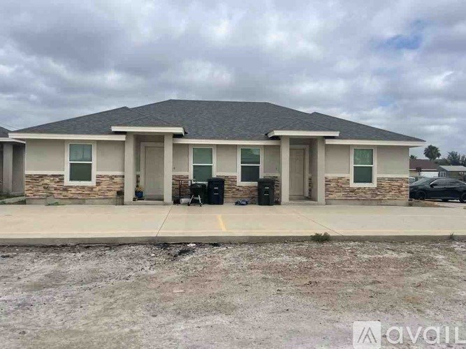 A two-story building with a grey roof and a parking lot in front.