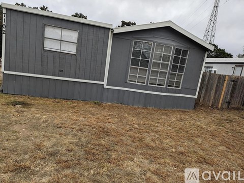 A grey house with a white window is available for rent.