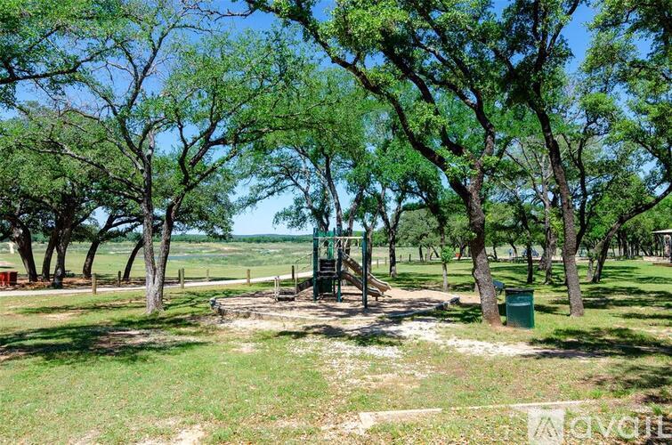A playground with a swing set surrounded by trees.