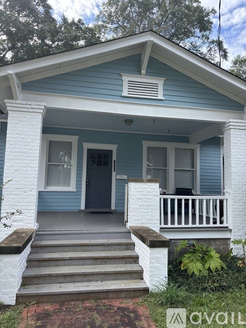 A blue house with a white porch and a black door.