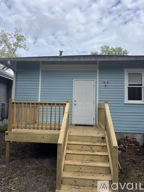 A small blue house with a white door and a wooden deck.