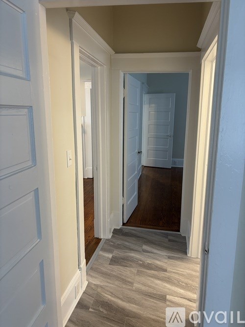 A hallway with a wooden floor and white walls.
