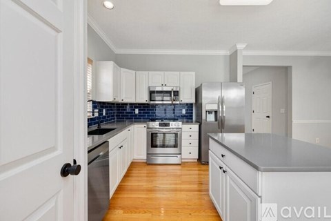 A kitchen with white cabinets and a blue backsplash.
