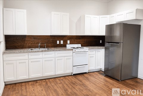A kitchen with white cabinets and a dark brown backsplash.