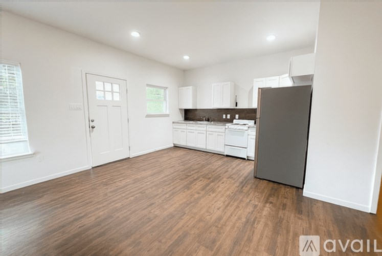 A kitchen with white cabinets and a wooden floor.
