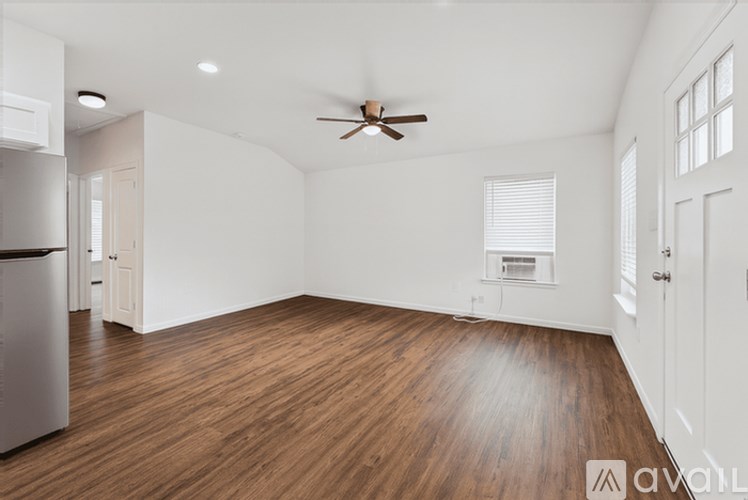 A spacious room with wooden floors and a ceiling fan.