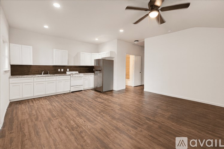 A spacious kitchen with white cabinets and a dark wood floor.