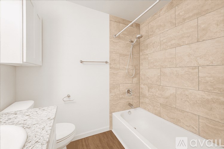 A bathroom with a beige tiled wall and a white bathtub.