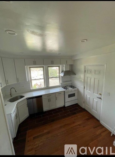 A kitchen with white cabinets and a window overlooking a backyard.